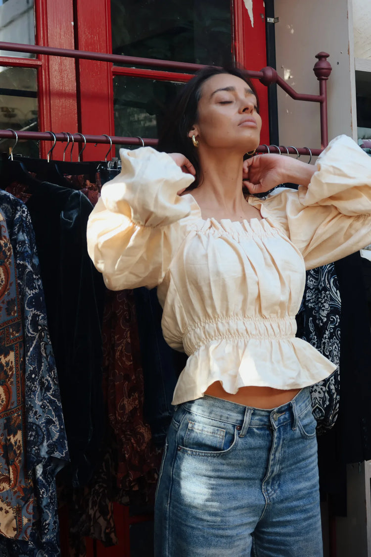 
                  
                    Blusa de lino color mantequilla con mangas abullonadas y pretina elasticada, vista de tres cuartos.
                  
                