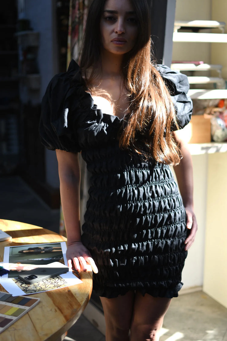 Vestido corto de lino negro con escote corazón, mangas abullonadas y cuerpo elasticado, vista frontal.